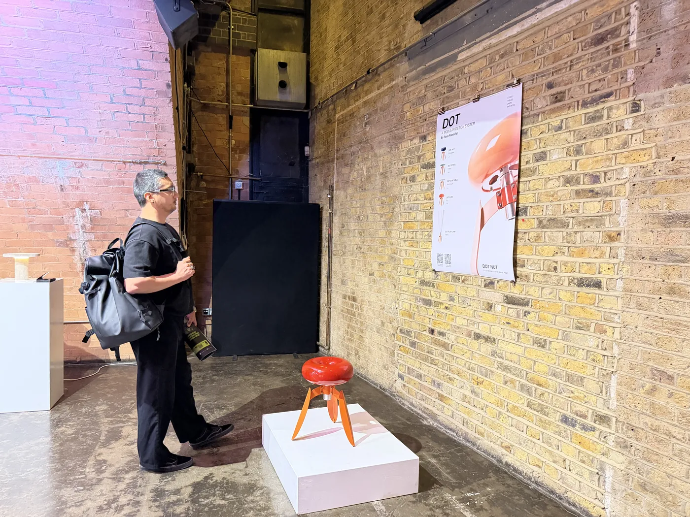 A visitor studying DOT Nut in the brick-walled exhibition space