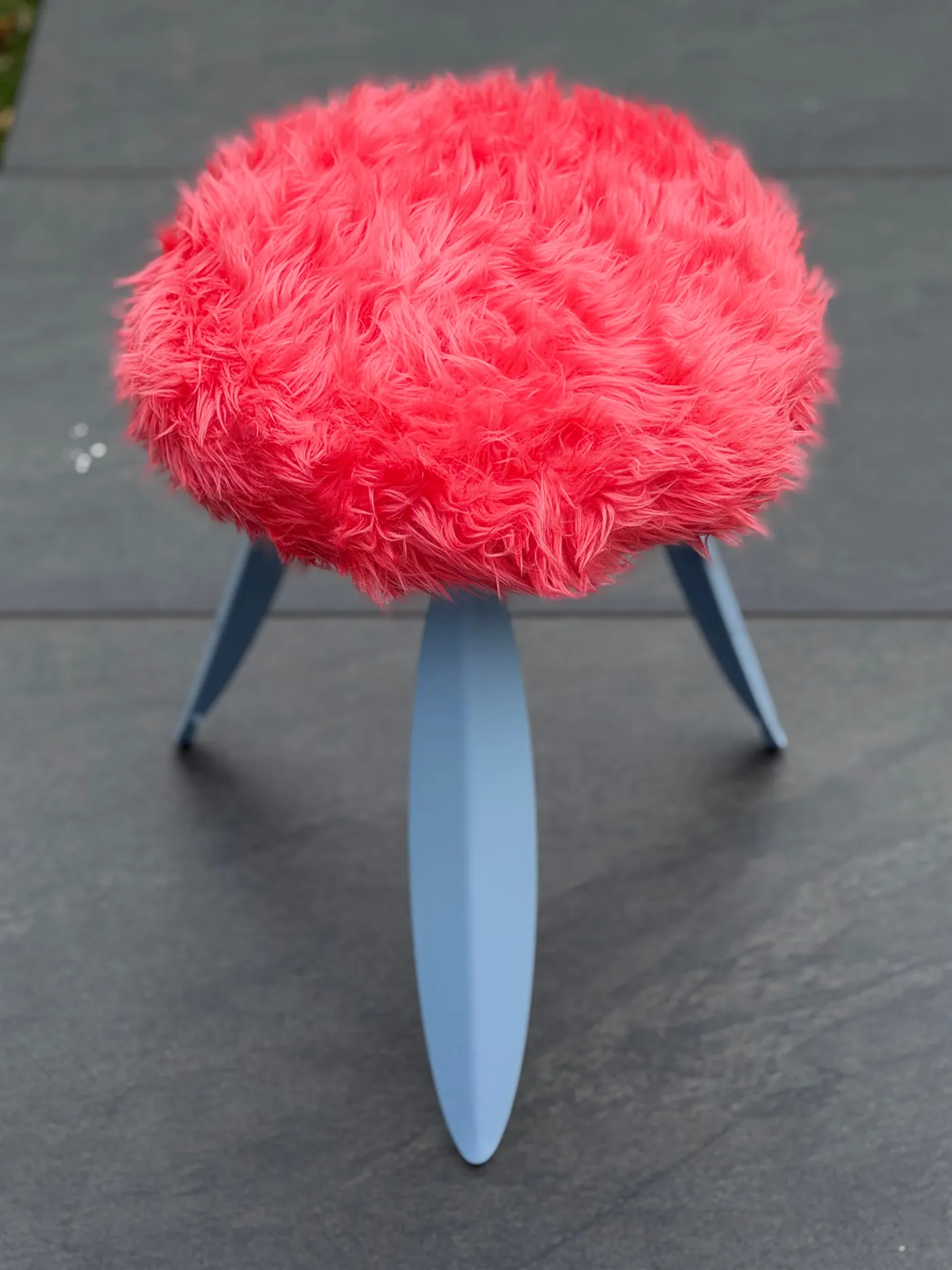 The coral fur seat up close, on grey paving