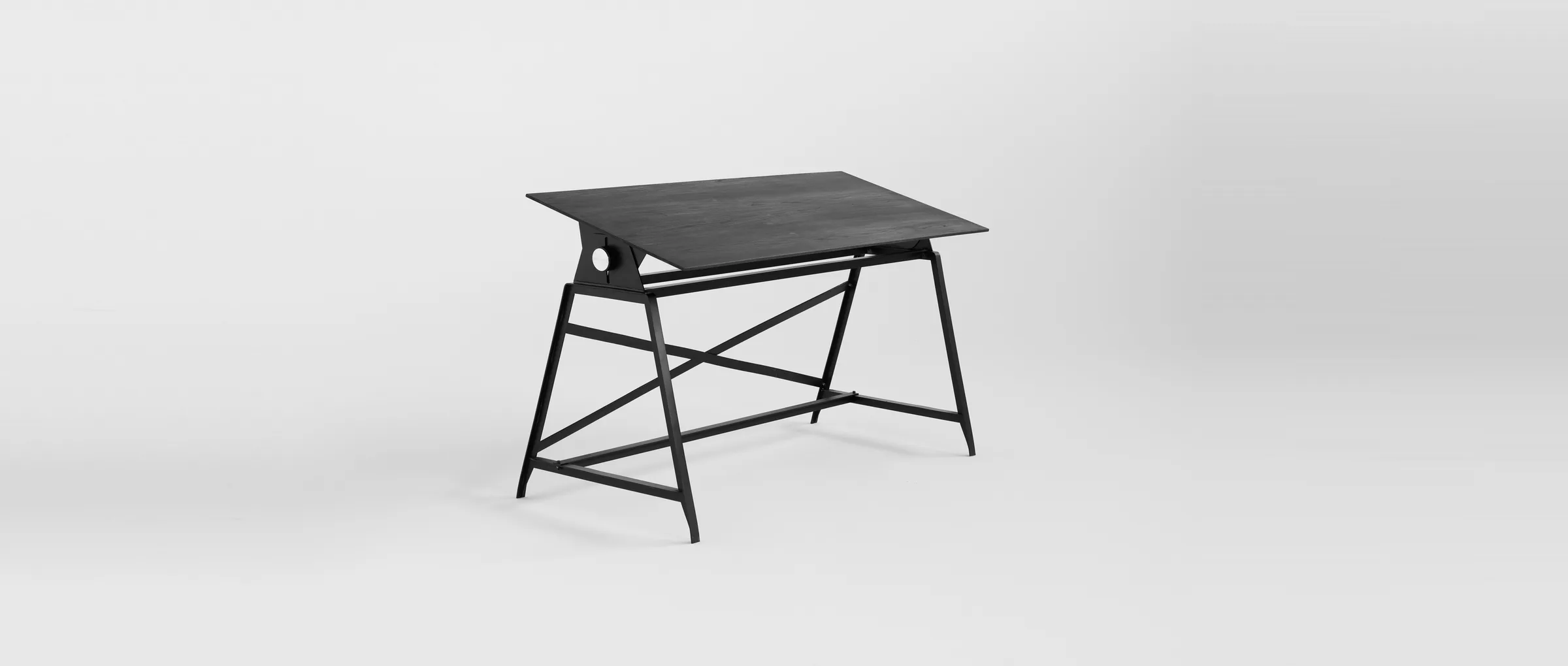 The Makran desk in full, its dark elm top tilted for drafting