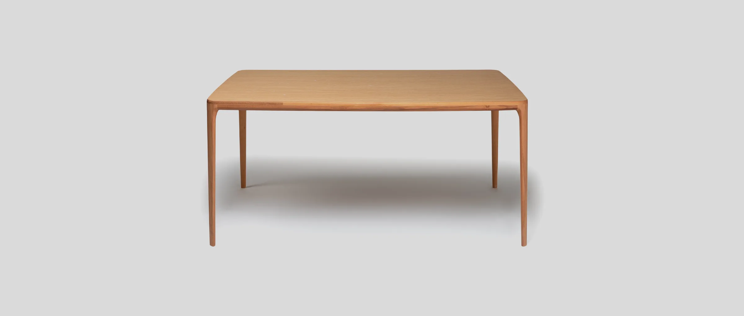 The Maroon dining table in solid wood, complete against soft grey